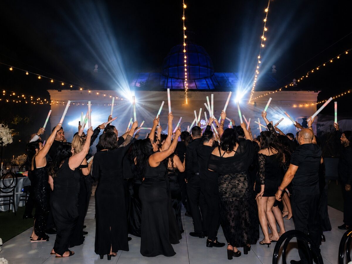 Packed dance floor full of energy under a club-style light show at a wedding
