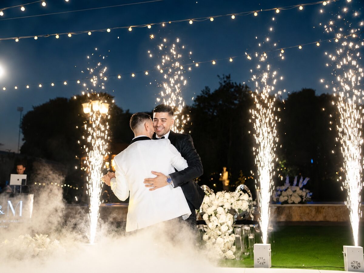 Couple dancing in the clouds as cold sparks fall behind them at their wedding