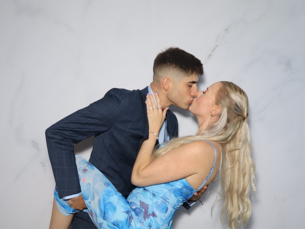 Couple posing with signs in the wedding photo booth