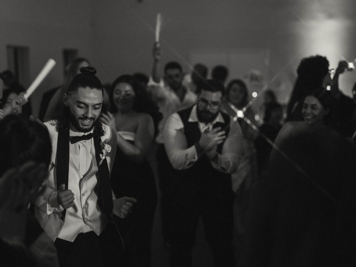 Groom dancing with guests on the wedding dance floor in black and white