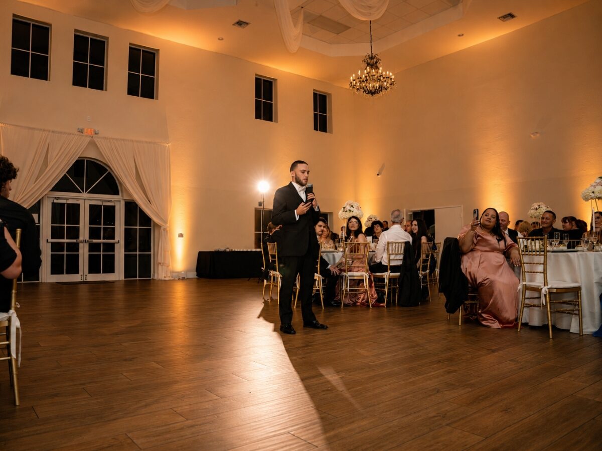 Amber uplighting on the venue walls as the best man gives his speech